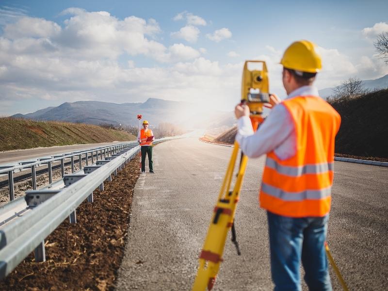 Surveyors conducting a boundary survey along a roadway to determine property lines